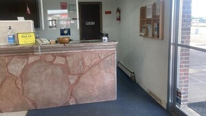 Ein Empfangsschalter mit einem Schild 'Privat', einem Schild 'Wähle 13' und einem Feuerlöscher an der Wand.