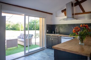 Eine moderne Küche mit einer großen Schiebeglas-Tür, die auf eine Terrassenfläche führt.