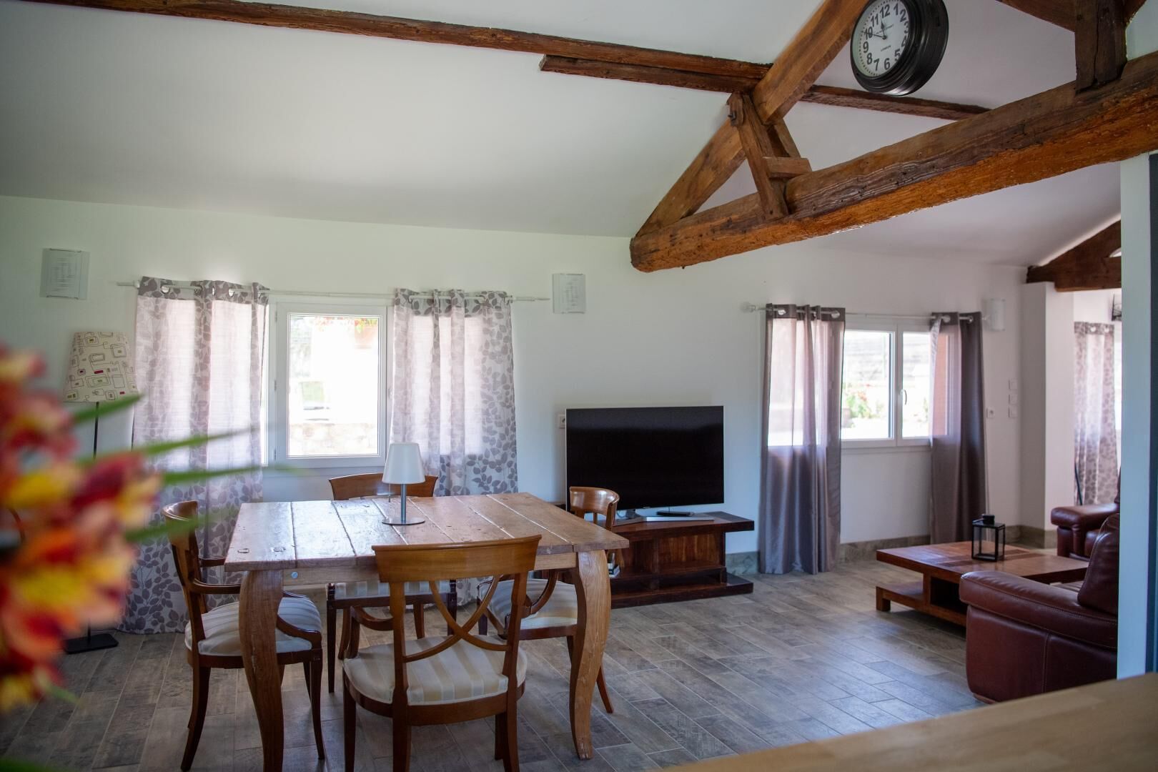 Un salon spacieux avec une table à manger en bois, des chaises, un téléviseur et un canapé en cuir.