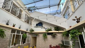 Un espace intérieur à plusieurs niveaux, doté d’un haut plafond, de guirlandes lumineuses et de plantes en pot.