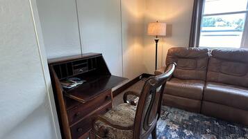 A room with a wooden desk, a leather sofa, and a patterned carpet.