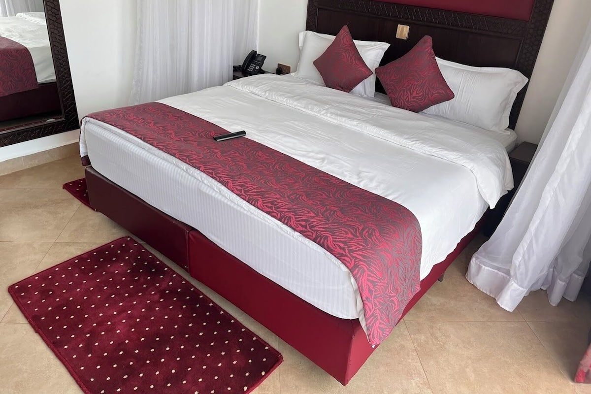 Une chambre d’hôtel avec un grand lit, un téléphone sur la table de chevet et un mur d’accent de couleur rouge.