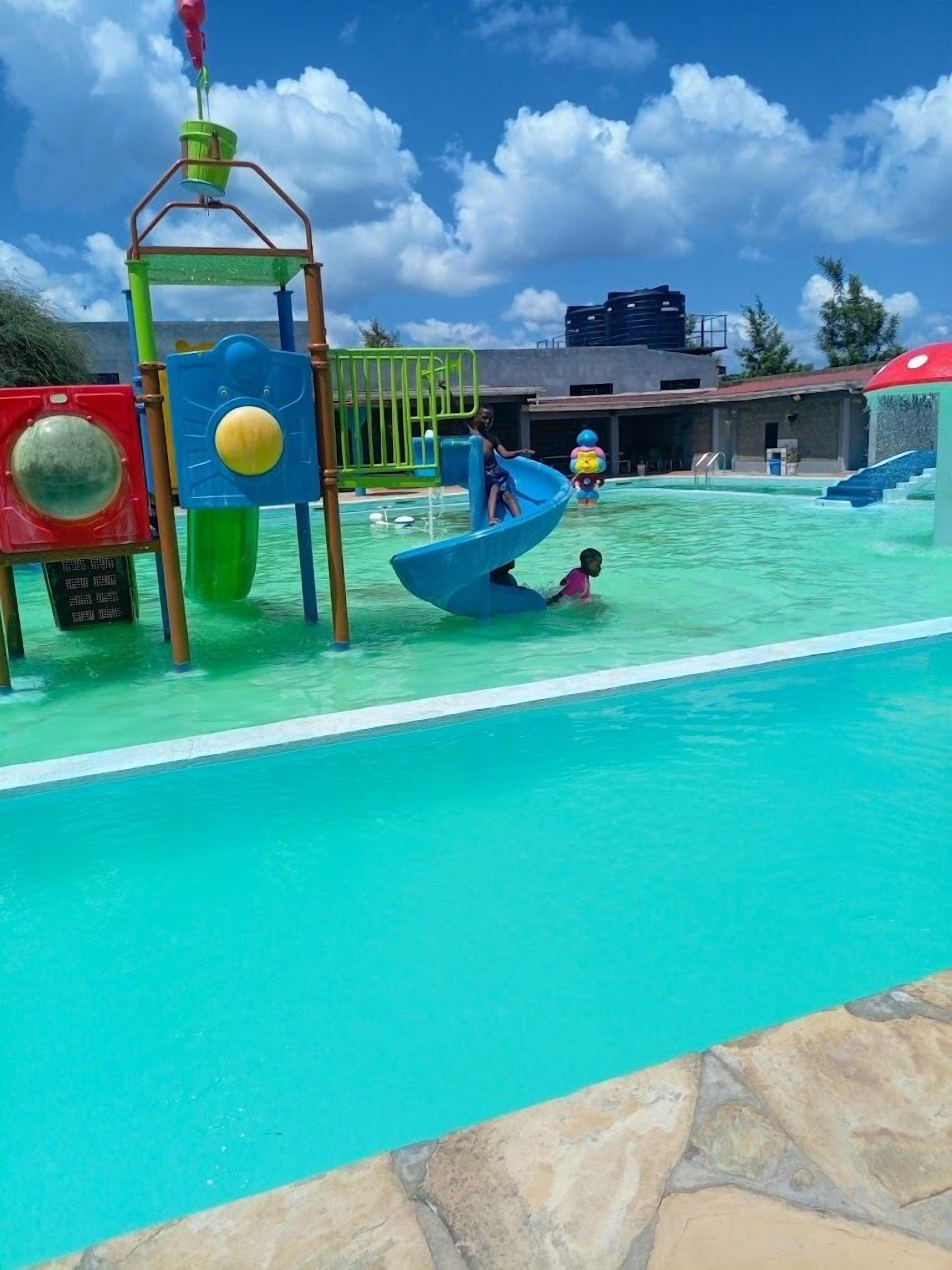 Ein Wasserpark mit einer blauen Rutsche und einem Wasserspielbereich.