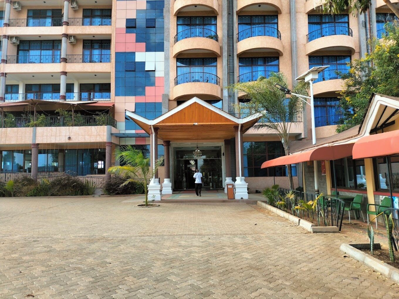 A multi-story hotel with a central entrance, outdoor seating area, and a landscaped courtyard.