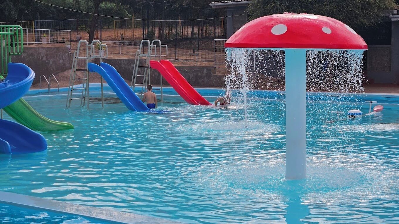 A swimming pool with multiple slides and a water fountain.