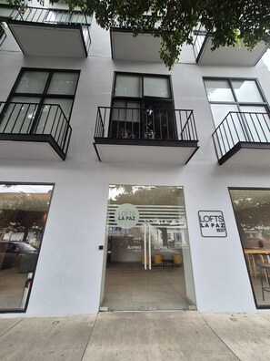 A modern building with a glass storefront, balconies, and a visible address sign. - Moderno Loft céntrico/Expo/Chapu (Guadalajara)
