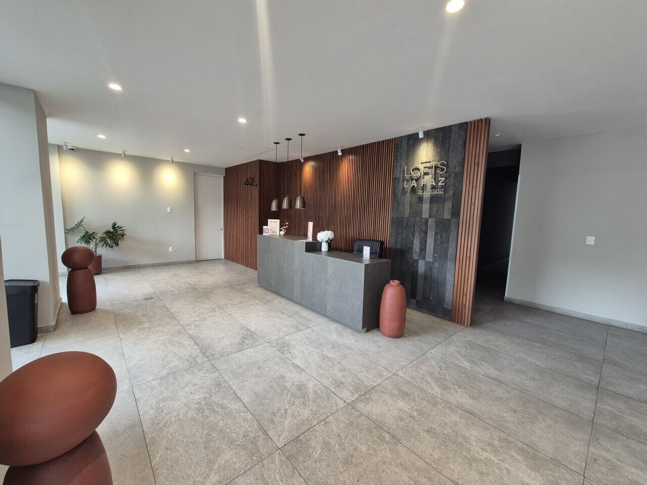 A modern reception area with a reception desk, seating, and a large wall with a logo.