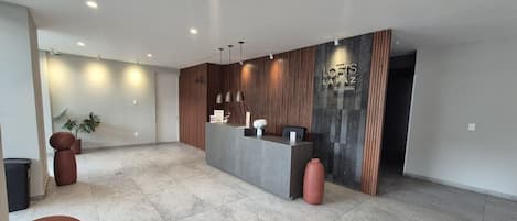 A modern reception area with a reception desk, seating, and a large wall with a logo.