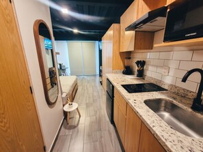 A modern kitchen with wooden cabinets, a stainless steel sink, and a built-in microwave. - Moderno Loft céntrico/Expo/Chapu (Guadalajara)