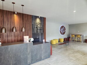 Un espace d’accueil au design moderne, comprenant un comptoir d’accueil, un coin salon et un mur décoratif.