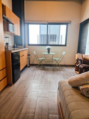 A compact kitchen with wooden cabinets, a built-in dishwasher, and a window overlooking a balcony. - Moderno Loft céntrico/Expo/Chapu (Guadalajara)