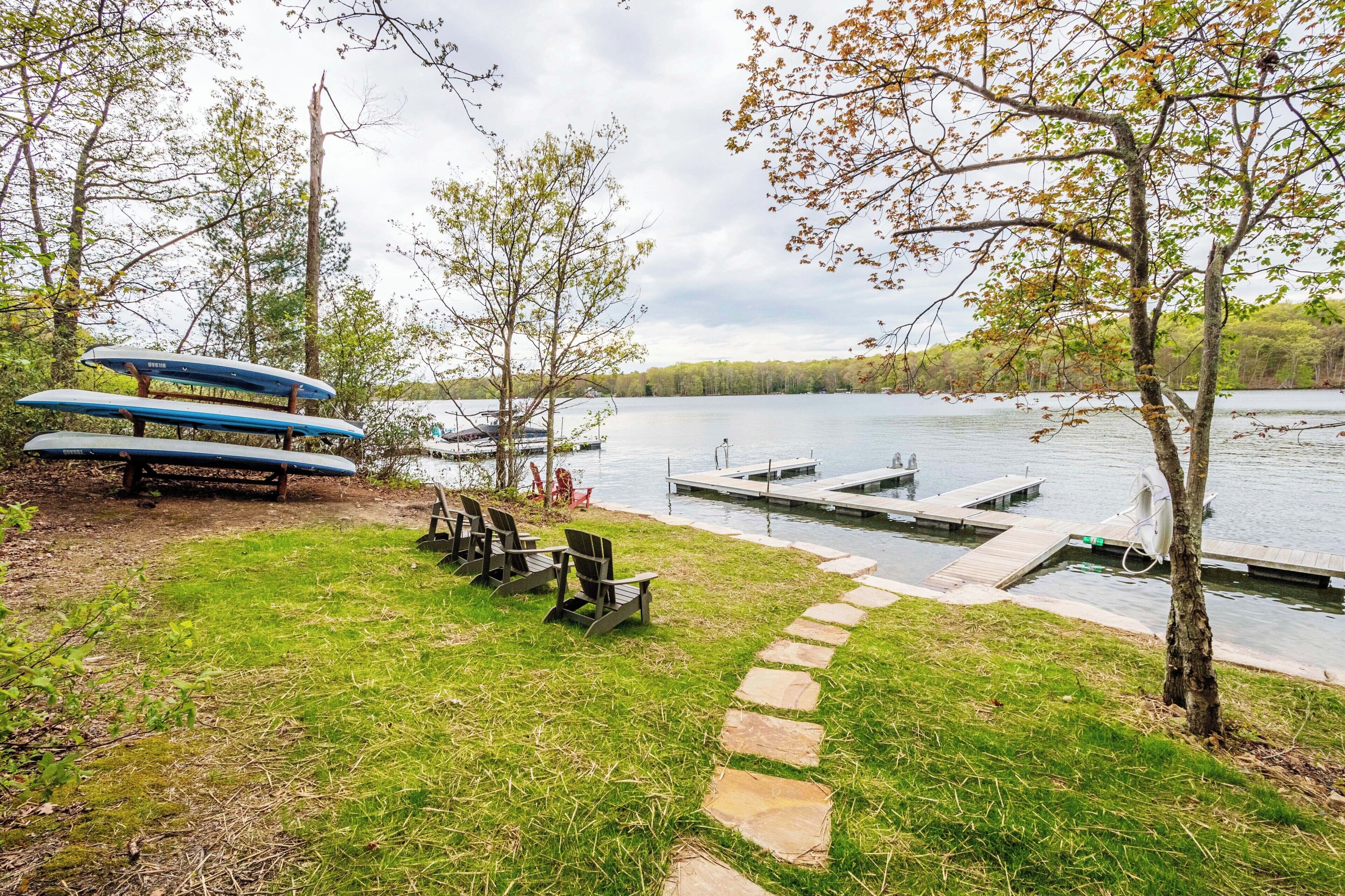 A lakeside setting with a dock, paddleboards, and outdoor seating.