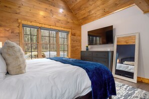 A bedroom with a large bed, wooden ceiling, a dresser, a mirror, and a TV. - Spruce Hollow-Brand NEW, Lake Access with Dock Slip, Dog Friendly, Hot Tub (Oakland)