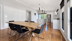 A modern kitchen with a wooden dining table, black chairs, and stainless steel appliances. - Snowgum Bright Retreat - 2 Houses, 1 Location (Bright)
