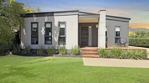A modern two-story house with a flat roof, large windows, and a well-maintained lawn. - Snowgum Bright Retreat - 2 Houses, 1 Location (Bright)