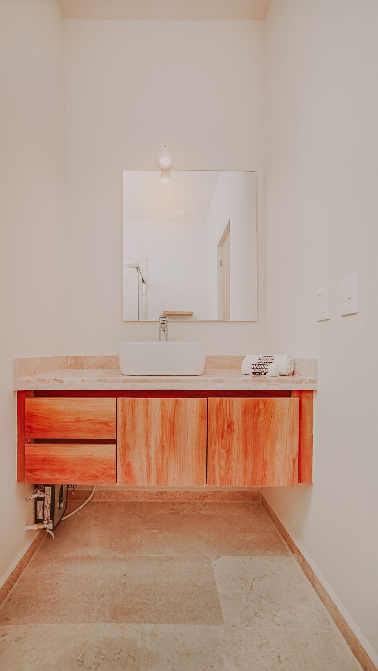 A bathroom with a large mirror, a sink, and wooden cabinets.