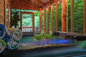 Eine Holzhütte mit Whirlpool, Handtüchern und zwei grüne Getränke auf einem Tisch.