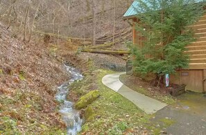 Eine Holzhütte mit einem Betonweg neben einem kleinen Bach.