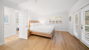 A bedroom with a wooden bed, white walls, and a ceiling fan. - 114 Managed by Brampton Park (Delray Beach)