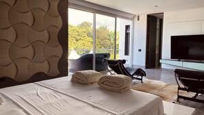 A modern hotel room with a large bed, a flat-screen TV, and a view of the outdoors.
