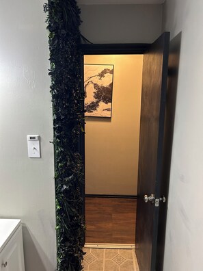 A hallway with a vertical garden, a door with a wooden finish, and a wall-mounted light switch. - Fully Furnished 3BR Home • Fast Wi-Fi • Parking • Near Uptown (Charlotte)