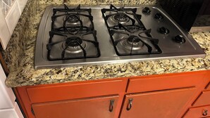 A kitchen with a stainless steel gas stove, granite countertop, and red cabinetry. - Fully Furnished 3BR Home • Fast Wi-Fi • Parking • Near Uptown (Charlotte)