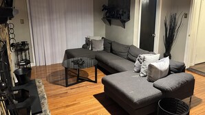 A living room with a grey sofa, a round coffee table, and a black side table. - Fully Furnished 3BR Home • Fast Wi-Fi • Parking • Near Uptown (Charlotte)