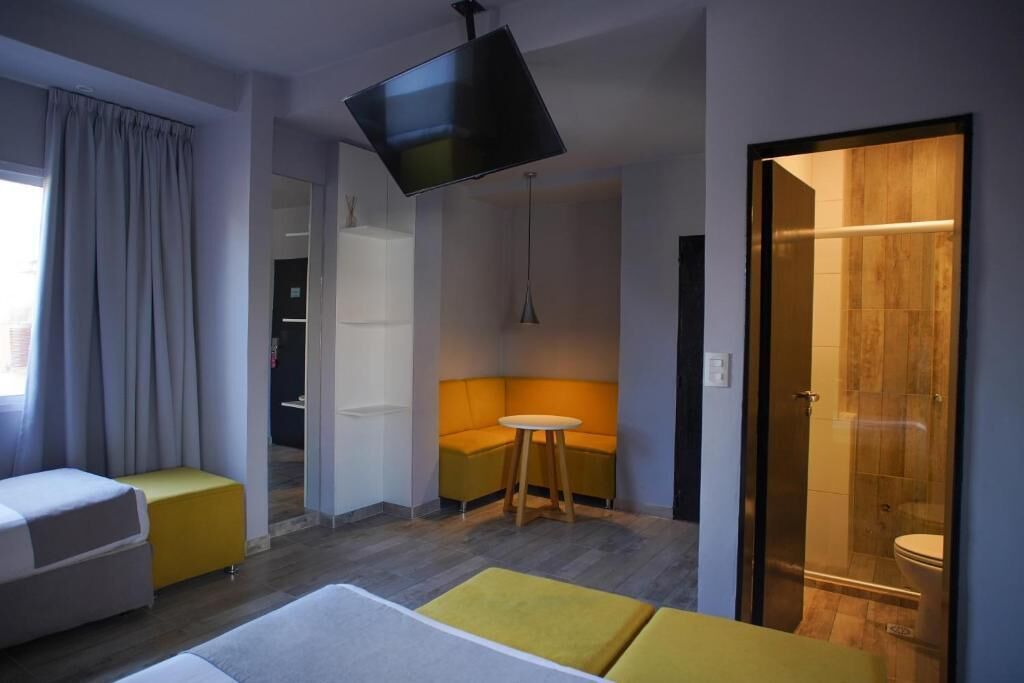 Une chambre d’hôtel moderne équipée d’une télévision à écran plat, d’un canapé, d’une petite table et d’une douche à parois de verre.