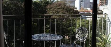 A balcony with a glass door, metal railing, and a round table with chairs.