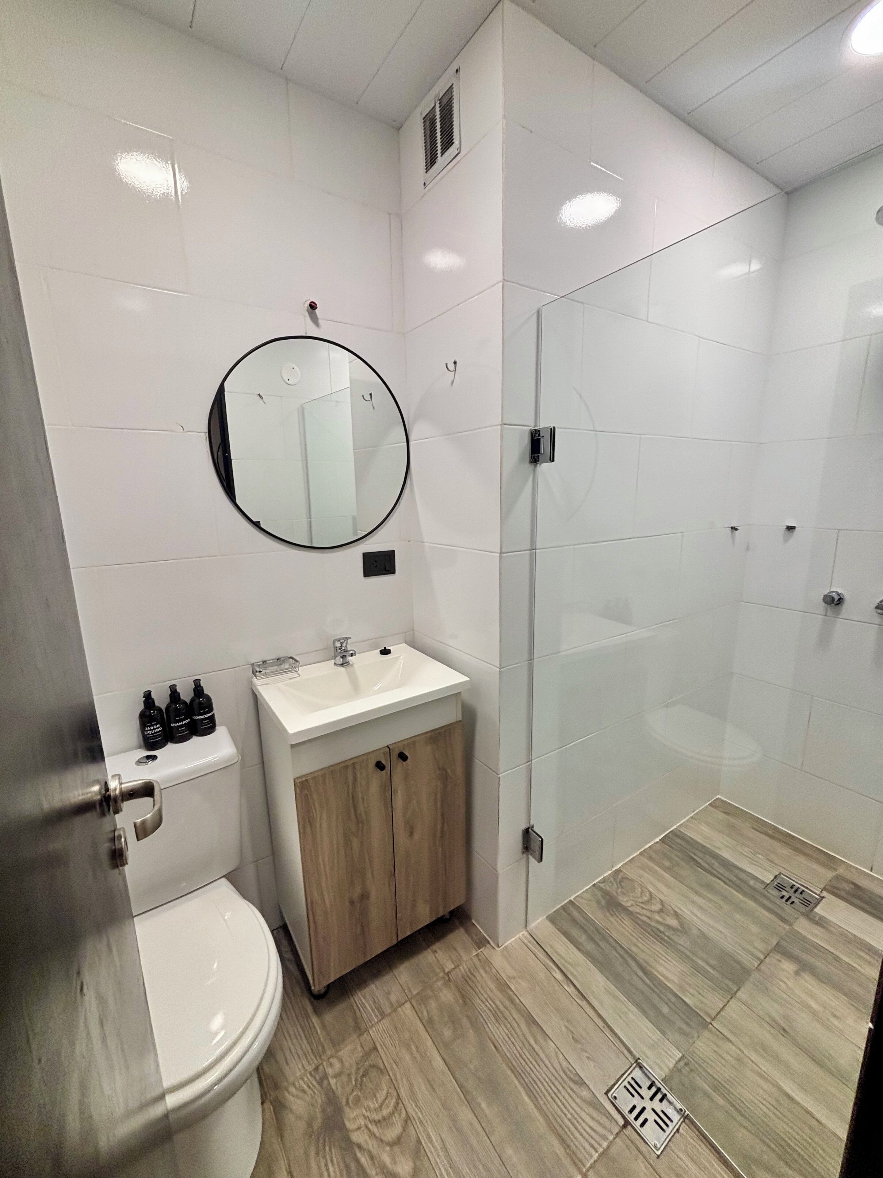 A modern bathroom with a toilet, sink, and glass shower enclosure.