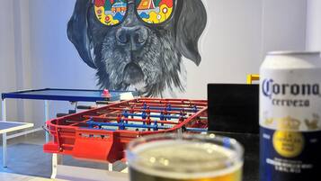 Ein Kicker, ein Bierglas und eine Corona-Dose auf einer Tischplatte.