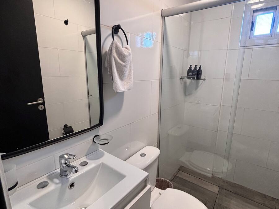 Une salle de bain moderne avec un lavabo blanc, un miroir et des toilettes.