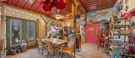 Un interior rústico con una mesa de comedor de madera, sillas y una puerta roja.