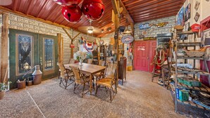 Un intérieur rustique avec une table à manger en bois, des chaises et une porte rouge.