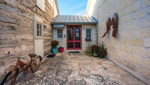 Une ruelle étroite, pavée de pierres, bordée d’un bâtiment rustique avec une porte rouge et une enseigne indiquant « BUREAU ».