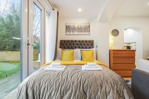 Ein Schlafzimmer mit einem großen Bett, einem Holzschrank, einem Spiegel und Blick ins Freie.