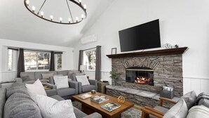 Una sala de estar moderna con chimenea de piedra, sofás grises y un televisor de pantalla plana.
