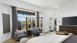 Un dormitorio amplio con una cama grande, dos sillones, una mesita y un televisor.