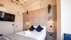 A hotel room with a large bed, a flat-screen TV mounted on the wall, bedside lamps, and a small bedside table with a plant. - Howth Marina Escape (Howth)