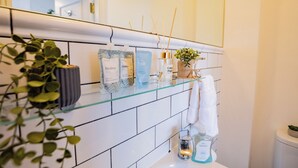 A bathroom with a glass shelf holding toiletries, a potted plant, and a towel. - Howth Marina Escape (Howth)