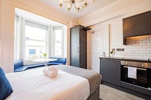 Een moderne hotelkamer met een groot bed, een zithoek met uitzicht, een kitchenette en een badkamer.