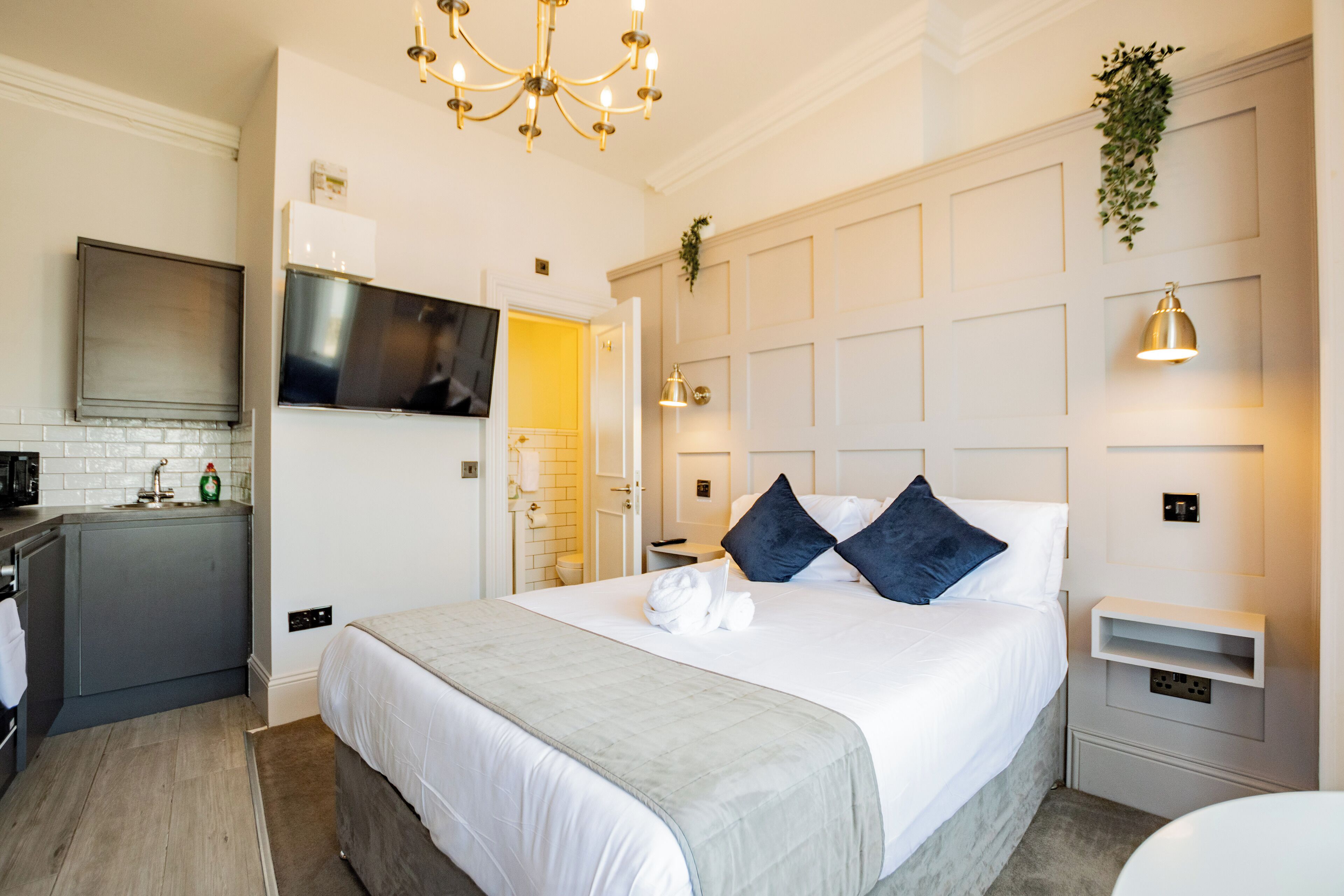 Habitación de hotel moderna con una cama grande, televisión, kitchenette y baño.