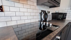 A modern kitchen with a black induction cooktop, a built-in oven, and a microwave. - Howth Marina Escape (Howth)