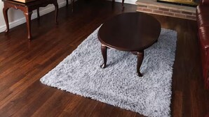 Un salon doté d’un parquet, d’une table basse ronde, d’un téléviseur à écran plat, d’une platine vinyle, d’une cheminée et d’un canapé en cuir rouge.