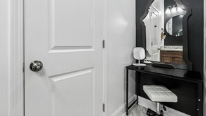 A white door with a silver handle, a black-framed mirror, and a small white stool.