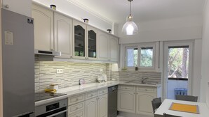 Een moderne keuken met witte kasten, een inbouwoven, een vaatwasser en een raam dat zorgt voor natuurlijk licht.