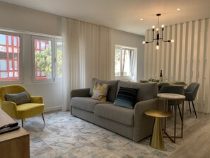 Un salon moderne avec un canapé gris, un fauteuil jaune et une petite table ronde.