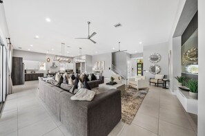 Una sala de estar moderna con un sofá gris, una mesita de centro y una escalera que conduce a un nivel superior.