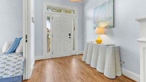 A hallway with a white door, a small table with a lamp, and a painting on the wall. - 4BR Oceanfront - Amazing Sunsets! Amenity Access incl. (Seabrook Island)