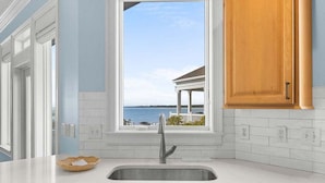 A kitchen with a large window, white cabinetry, and a view of the ocean. - 4BR Oceanfront - Amazing Sunsets! Amenity Access incl. (Seabrook Island)